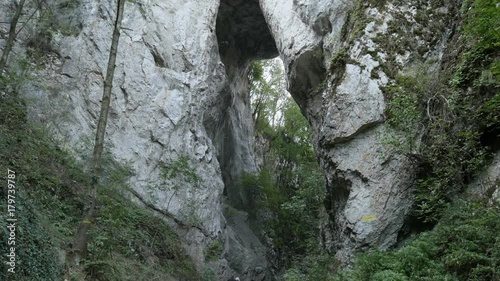 Hikers under natural stone bridge slow tilt footage - Beautiful nature in Eastern Serbia photo