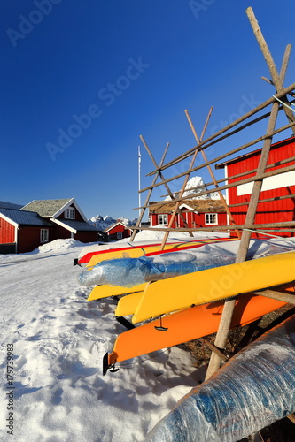 Kayaks-red cottages-rorbuer in Reine village. Helvetestinden-Stamprevtinden-Moltbaertinden-Breiflogtinden-Olstinden mounts background. Moskenesoya-Lofoten-Nordland-Norway. 0307