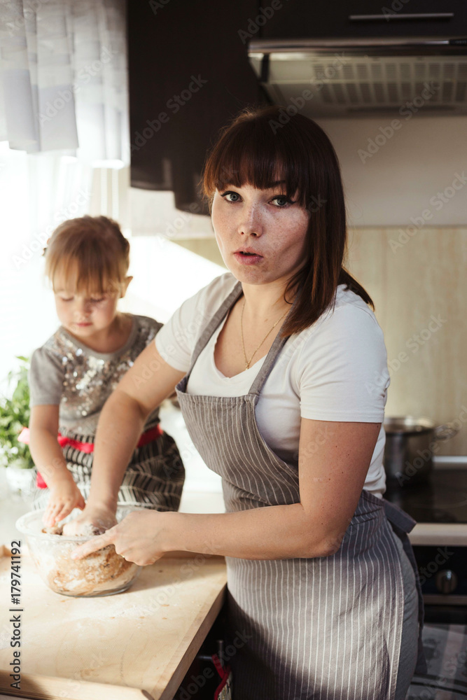 Mother and daughter kneading dough for Christmas gingerbread cookies. Lifestyle image at home kitchen.