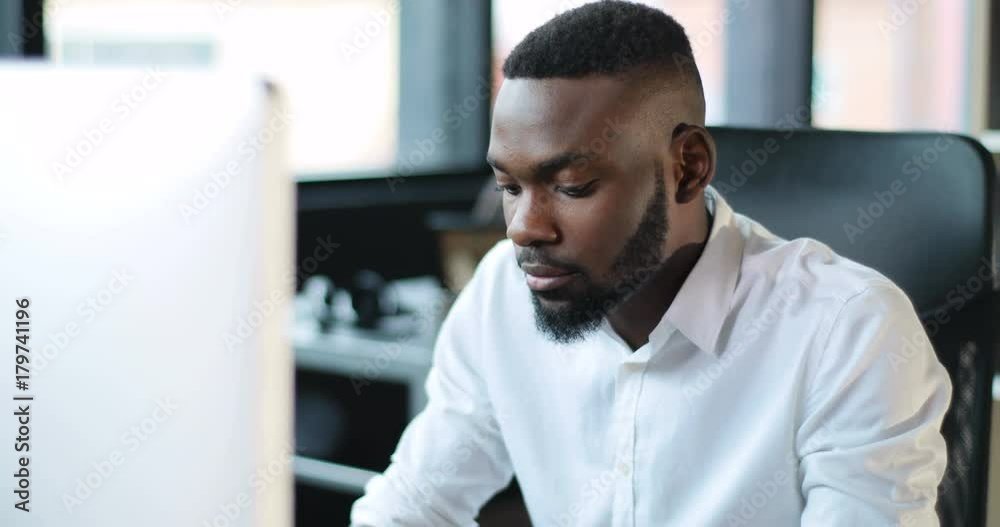 Serious young black man with a beard working use computer in office technology african american businessman casual communication entrepreneur successful person portrait smart business Slow Motion Shot Serious young black man with a beard working use computer in office technology african american businessman casual communication entrepreneur successful person portrait smart business Slow Motion Shot