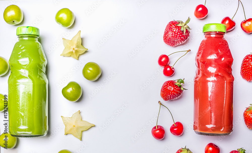 Obraz premium appetizing healthy smoothies from carambola and green plum, strawberries and sweet cherries in glass bottles on a white wooden rustic background, top view