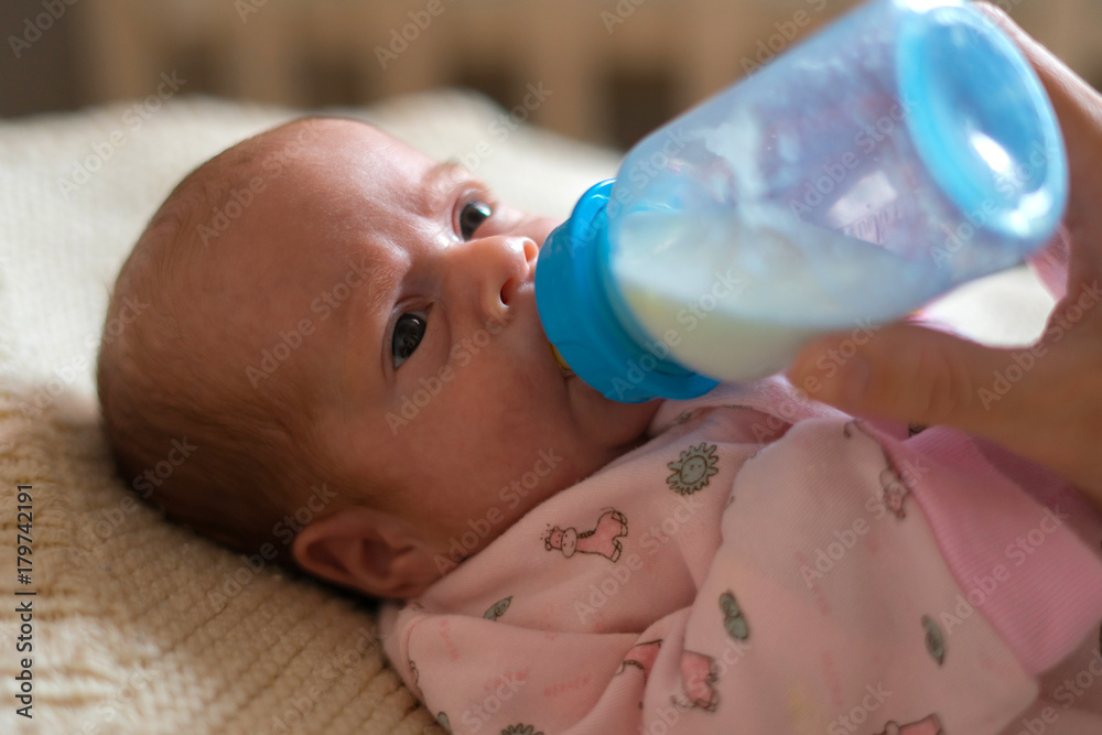 Mother feeding baby girl from the baby bottle Mother feeding baby girl from the baby bottle