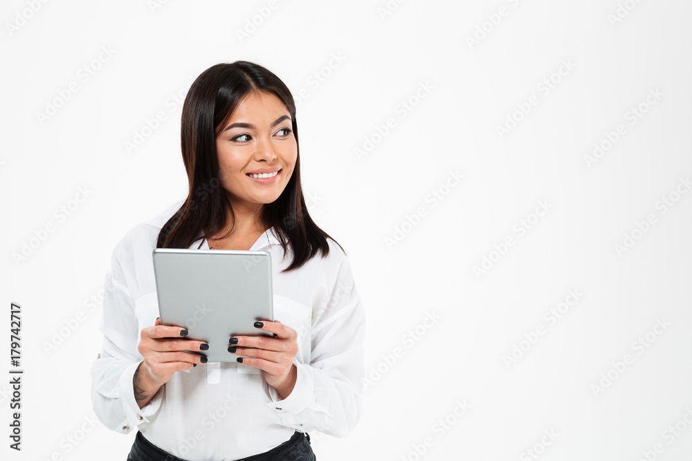 Cheerful young asian lady chatting by tablet computer. Looking aside. Cheerful young asian lady chatting by tablet computer. Looking aside.