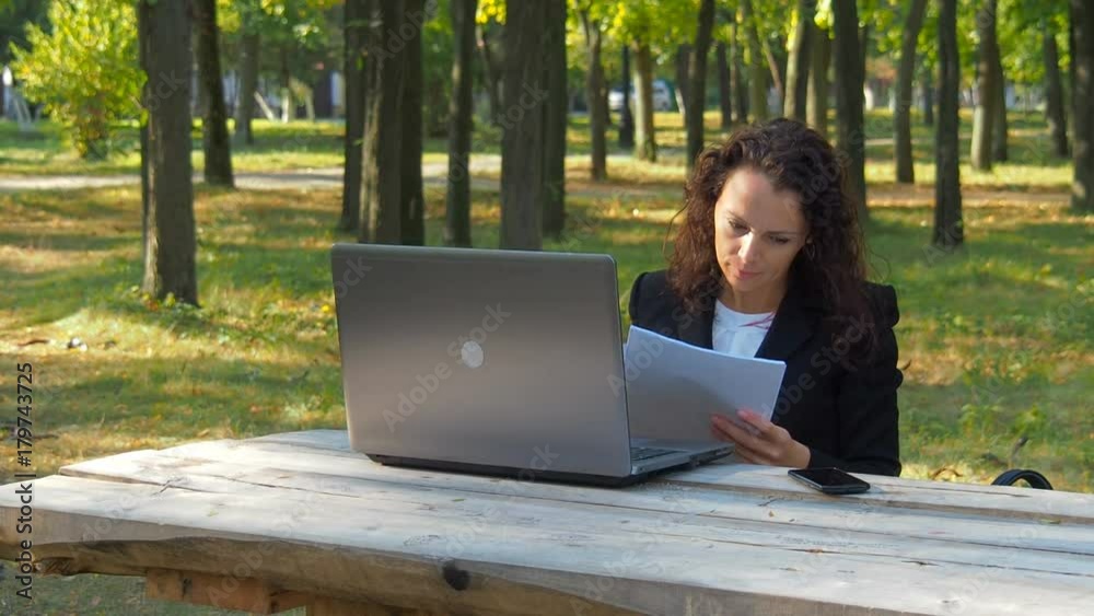 Business woman with laptop and documents working on nature.