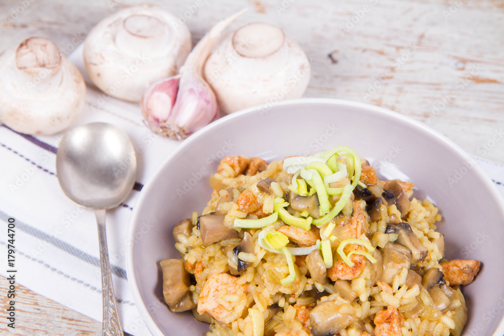 Risotto with mushrooms and chicken decorated with leek on a wooden background