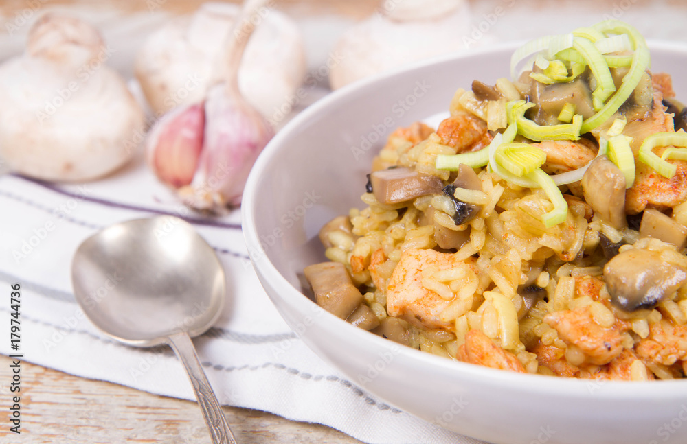 Risotto with mushrooms and chicken decorated with leek on a wooden background