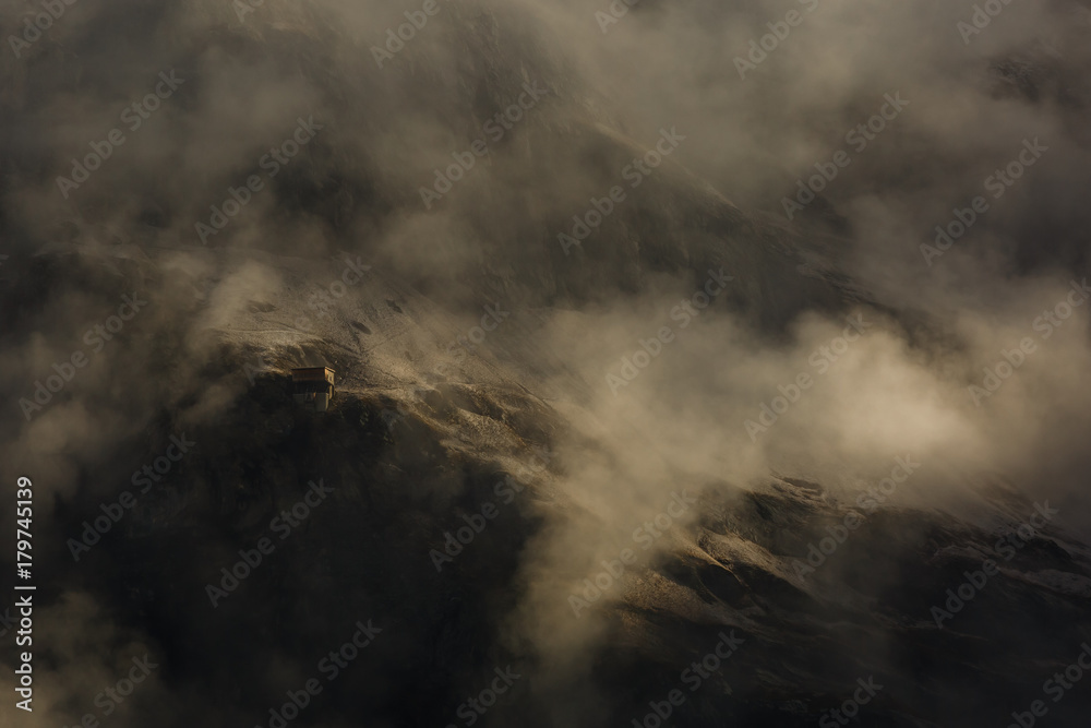 Building house for skiers skiing on the top of a snowy mountain with fog, blizzard in background Building house for skiers skiing on the top of a snowy mountain with fog, blizzard in background