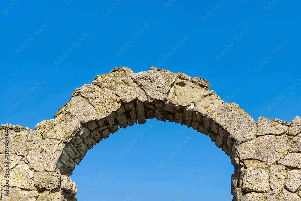Stone arch against a blue sky.