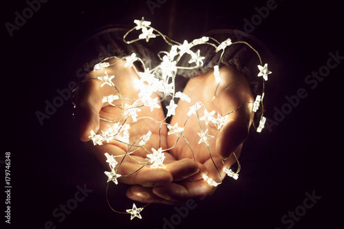 Christmas lights in man's hands. Decoration, holidays and people concept.