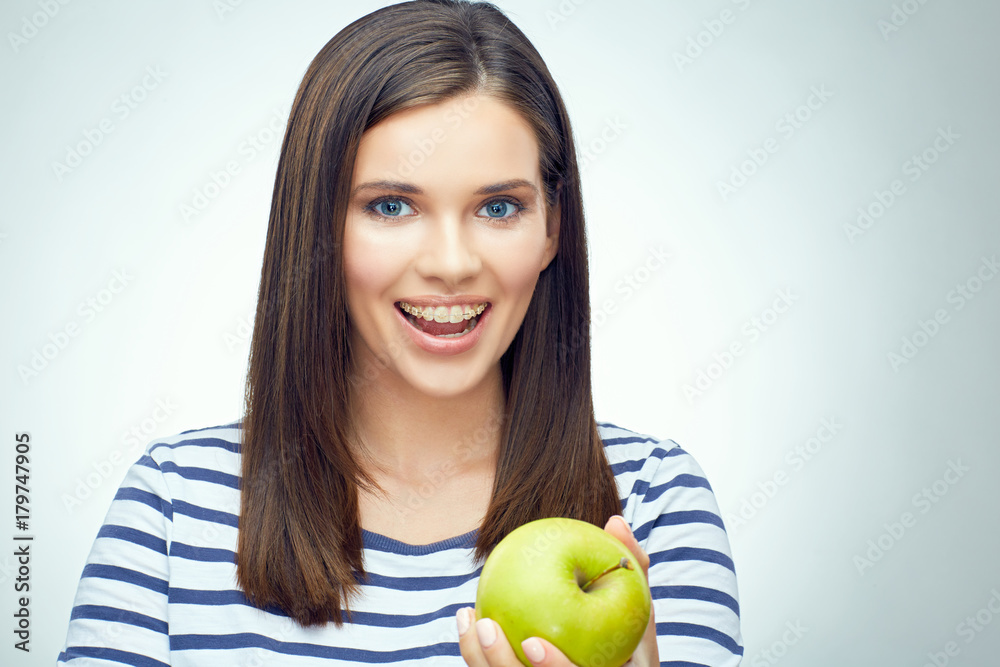 Girl smile with teeth and toothy braces holding green apple Girl smile with teeth and toothy braces holding green apple