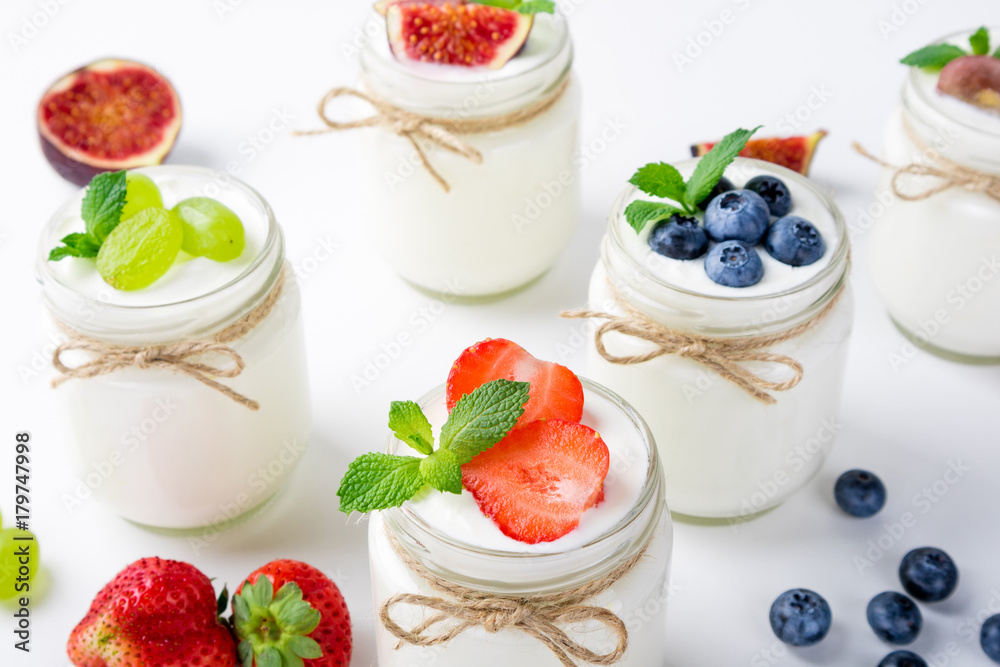 Fresh yogurt with berries in glass jars. Dairy products. Healthy food, dieting and breakfast concept Fresh yogurt with berries in glass jars. Dairy products. Healthy food, dieting and breakfast concept