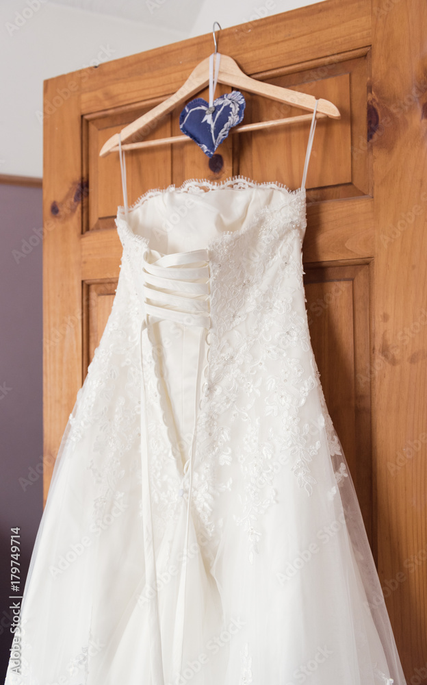 A beautiful elegant cream and white Wedding dress hanging on the door in the bride