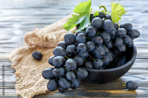 Delicious black grapes in a wooden bowl.