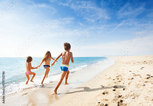 Kids running along beach during summer vacation