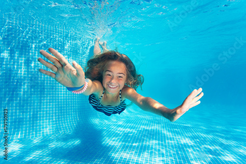 Portrait of preteen girl diving with fun in pool