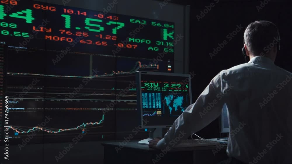 Adult man working in office of exchange and driving lively trade while speaking with headset.