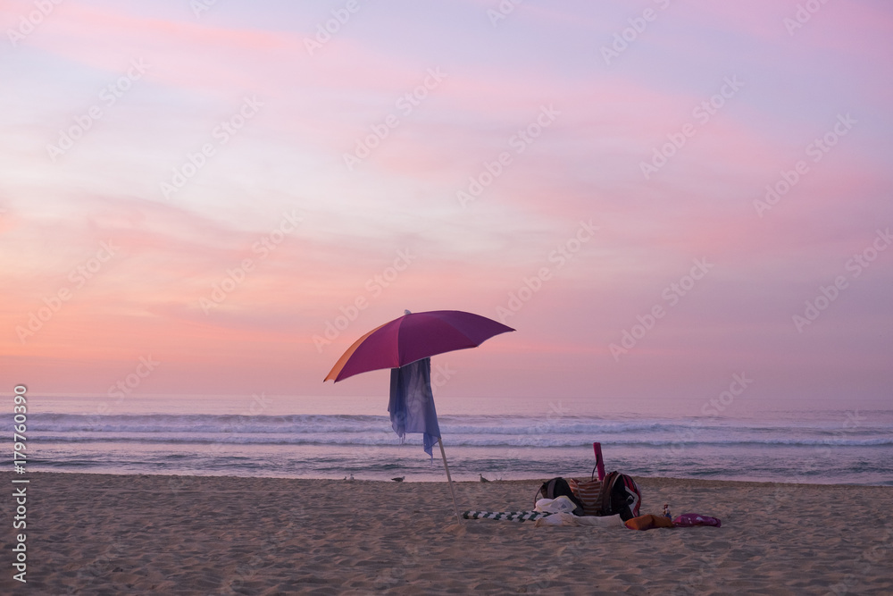 Beach umbrella on beach at sunset in San Sebastian city