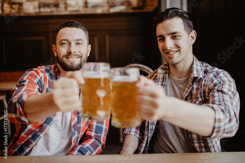 happy male friends drinking draft beer at bar or pub and clinking glasses