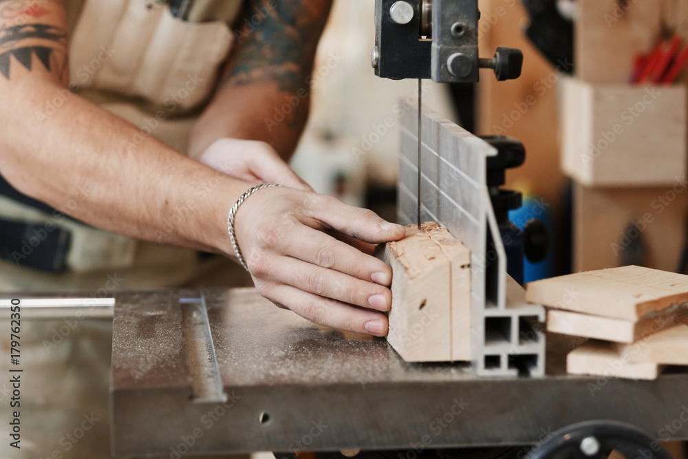 Carpenter's hands cutting wood with tablesaw in workshop. carpenter's hands close up