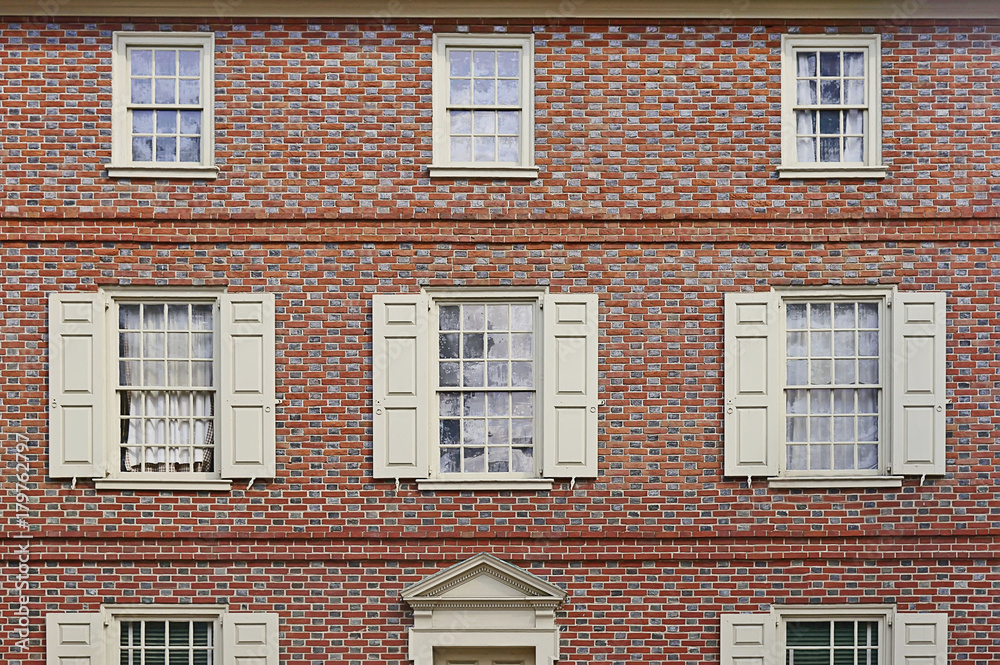 Obraz premium Old red brick wall with white shutters