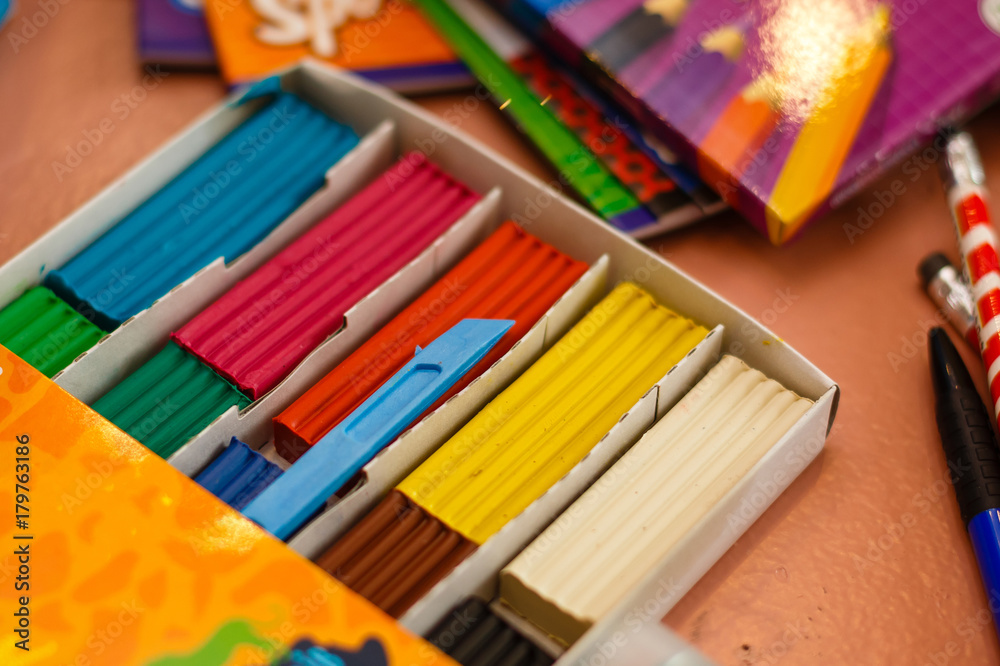 Naklejka premium Top view of a white plastic box with colorful plasticine bars greenish blue yellow red 