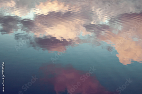 reflection of blue sky with white clouds in water, abstract background.