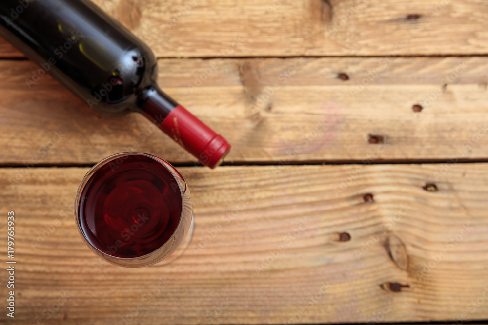 Red wine bottle and glass on wooden background, copy space