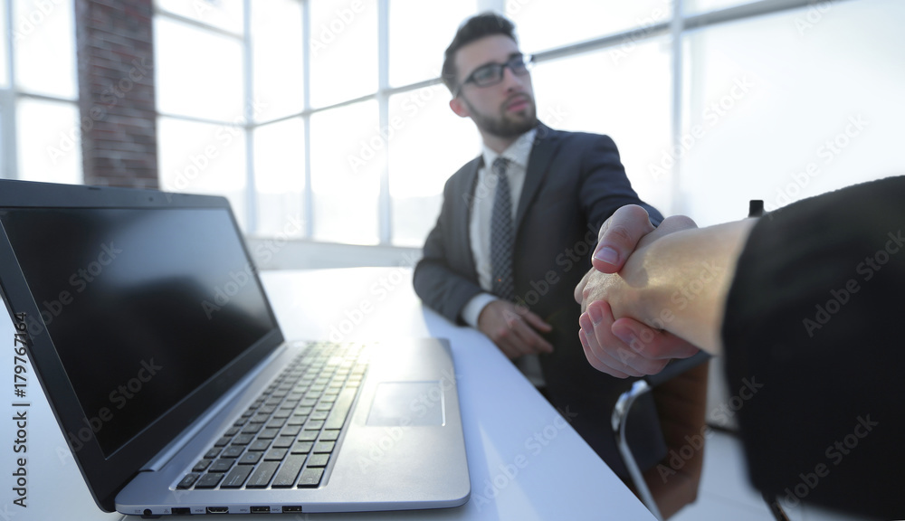 Business partners handshaking over business objects on workplace Business partners handshaking over business objects on workplace