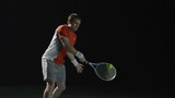 Man hitting tennis ball with racket, isolated on black