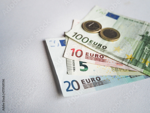 Euro banknotes and coins on white background.