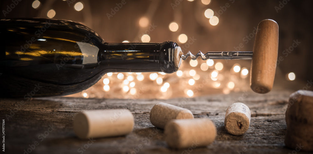 Cork screw and wine bottleOpening a wine bottle with corkscrew on defocused lights as holiday concept