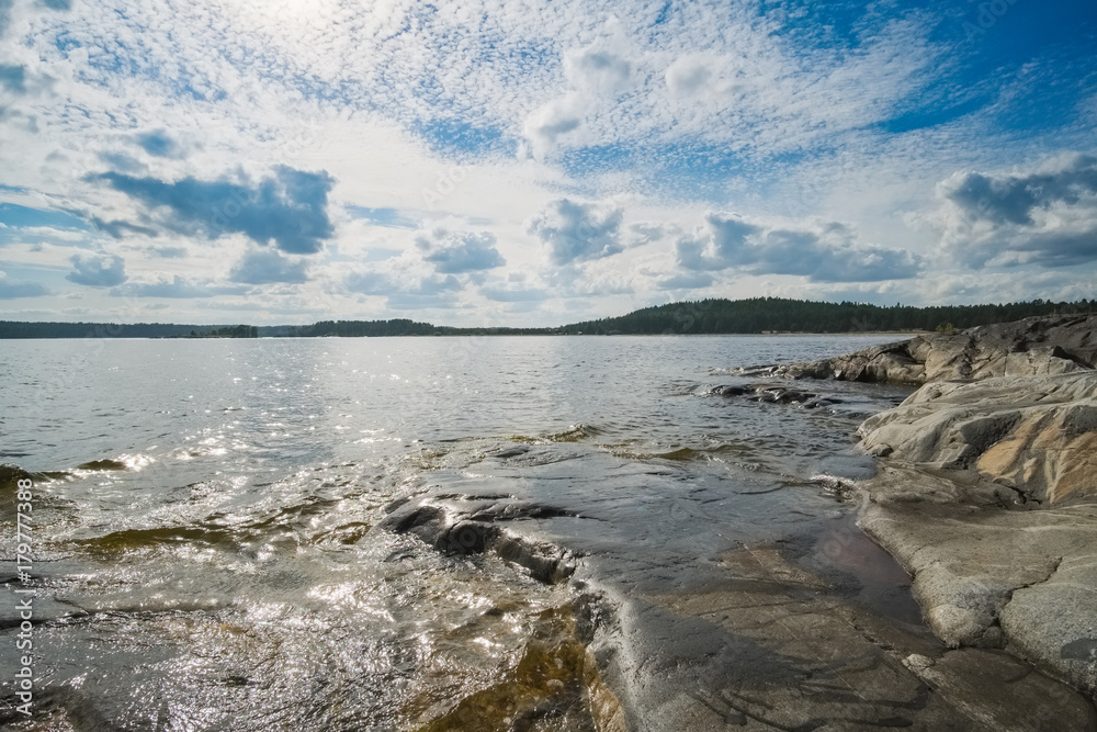 Fototapeta premium Landscape on a large lake with a stone beach on a summer day. Ladoga Lake, Karelia