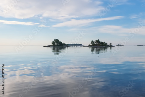 Landscape on a large lake with islands on a summer morning with beautiful sky and reflections. Lake Ladoga, Karelia