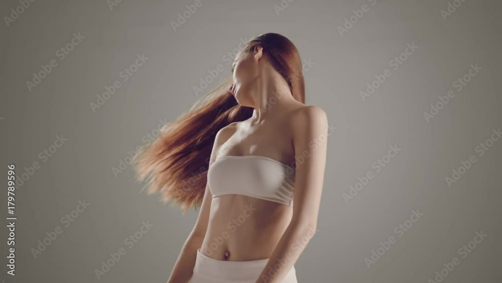 Beautiful fashion model young Caucasian girl sensual hair movement over a minimal grey background in slow motion prores .