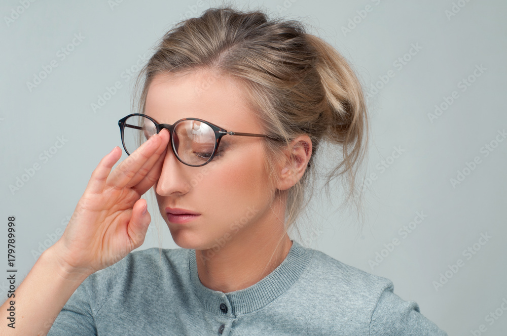 Tired woman with eyeglasses has eyes pain