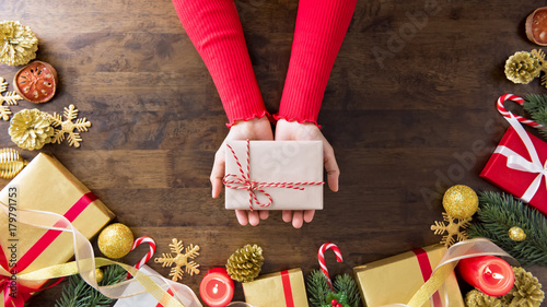 Hands showing Christmas gift box on wood table