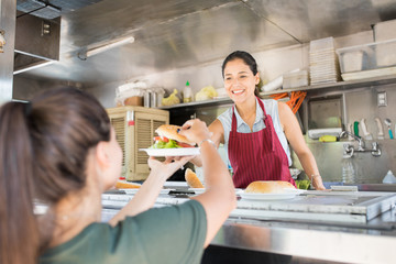 Happy woman selling hamburgers in food truck