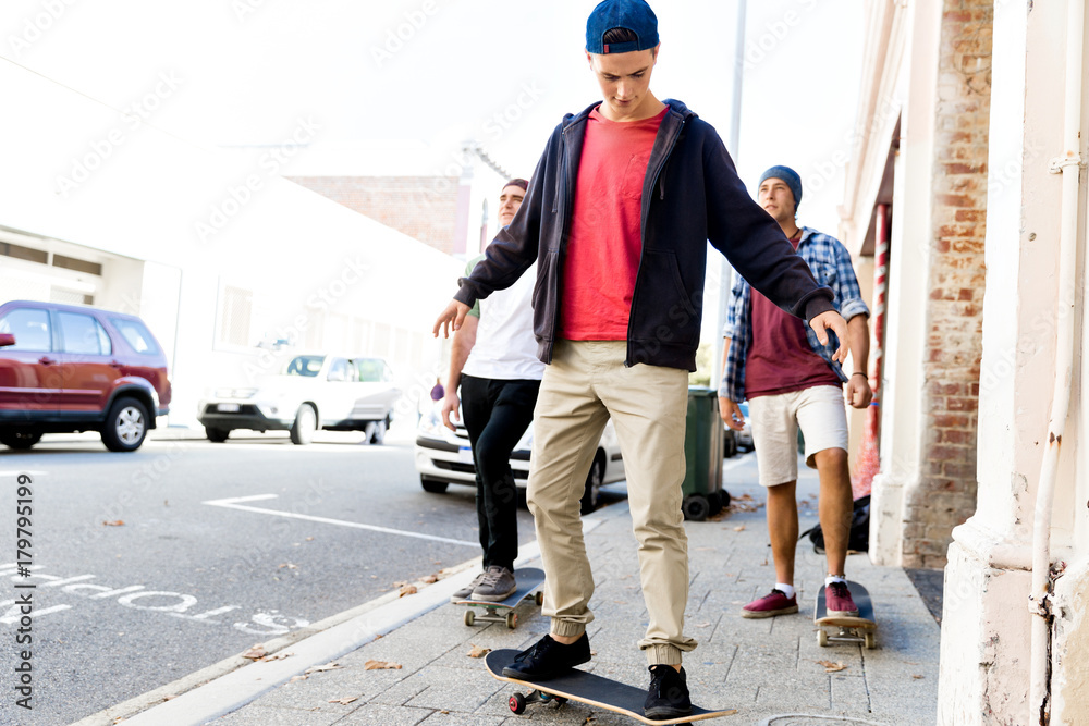 Teenage friends walking at the street with skateboards Teenage friends walking at the street with skateboards