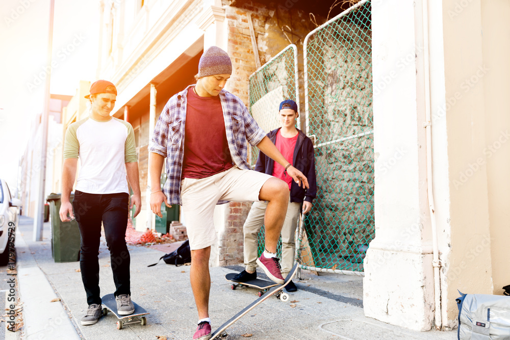 Fototapeta premium Teenage friends walking at the street with skateboards