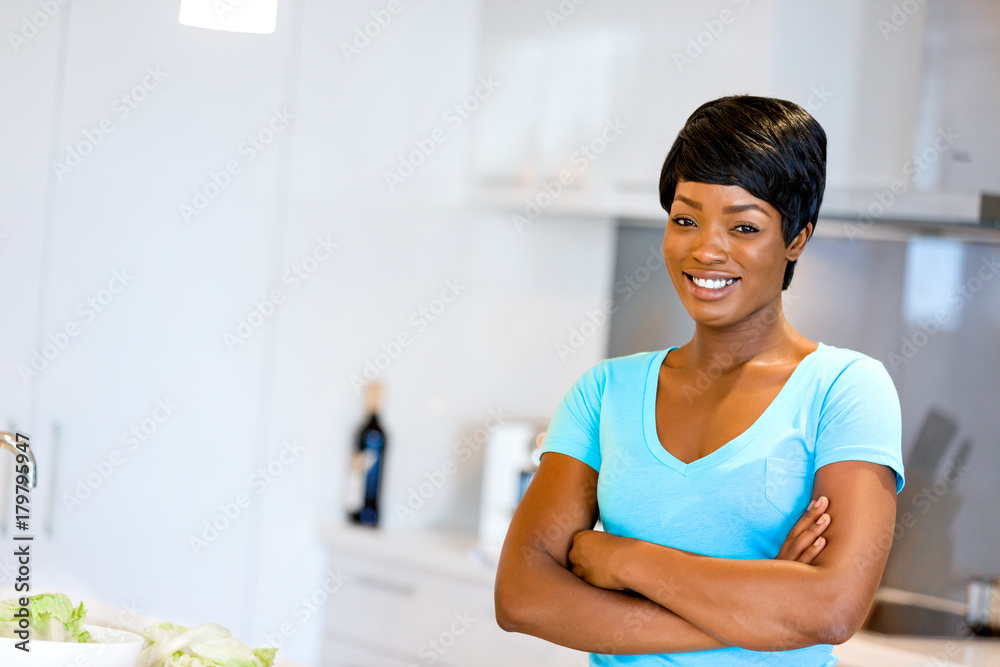 Beautiful woman standing in the kitchen and smiling Beautiful woman standing in the kitchen and smiling