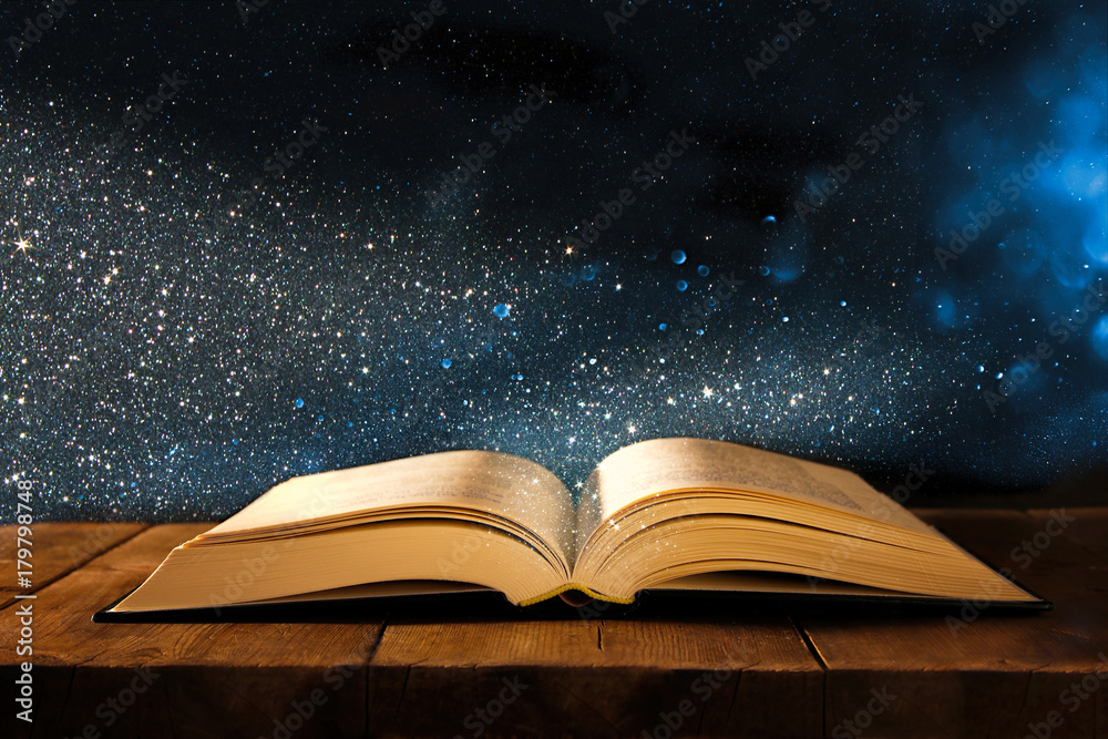 Fototapeta premium obraz otwartej antycznej książki na drewnianym stole z nakładką brokatu.