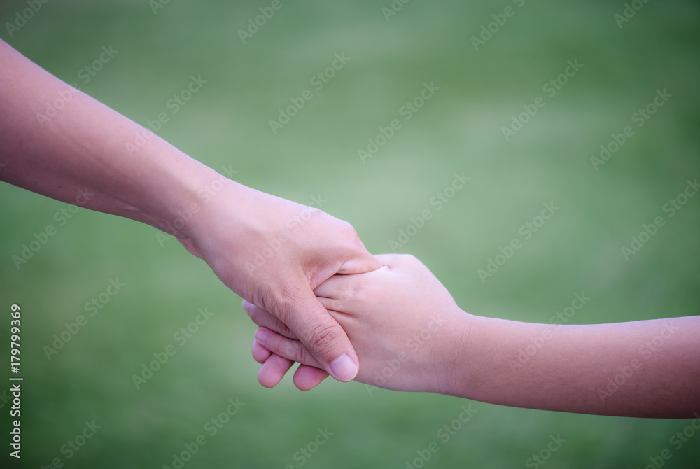 Mother holding a hand of his son with green glass background. Love , famiy and mother day concept. Mother holding a hand of his son with green glass background. Love , famiy and mother day concept.