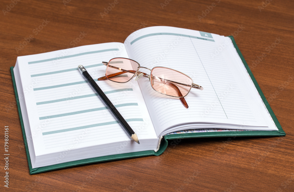 Pencil and glasses on the businessman's diary Pencil and glasses on the businessman's diary