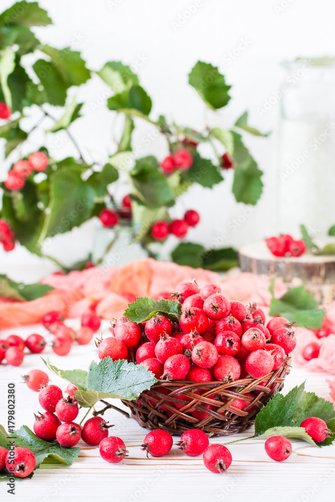Berries and leaves of hawthorn in a wicker basket on a wooden table