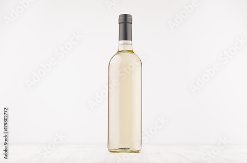 Transparent wine bottle with white wine on white wooden board, mock up. Template for advertising, design, branding identity.