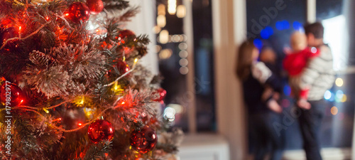 Christmas scene with happy family of four  tree gifts and window in blurred bokeh background  copy space