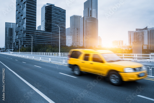 a yellow car driving on inner city road, china