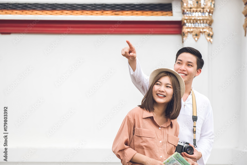 Naklejka premium Asian couple tourists visiting Thai temple in Bangkok Thailand on summer holidays