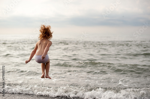 Red-haired girl is jumping over the waves