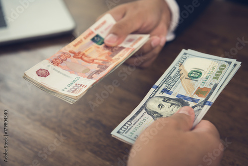 Hand holding US dollar bills trading with Russian ruble currency